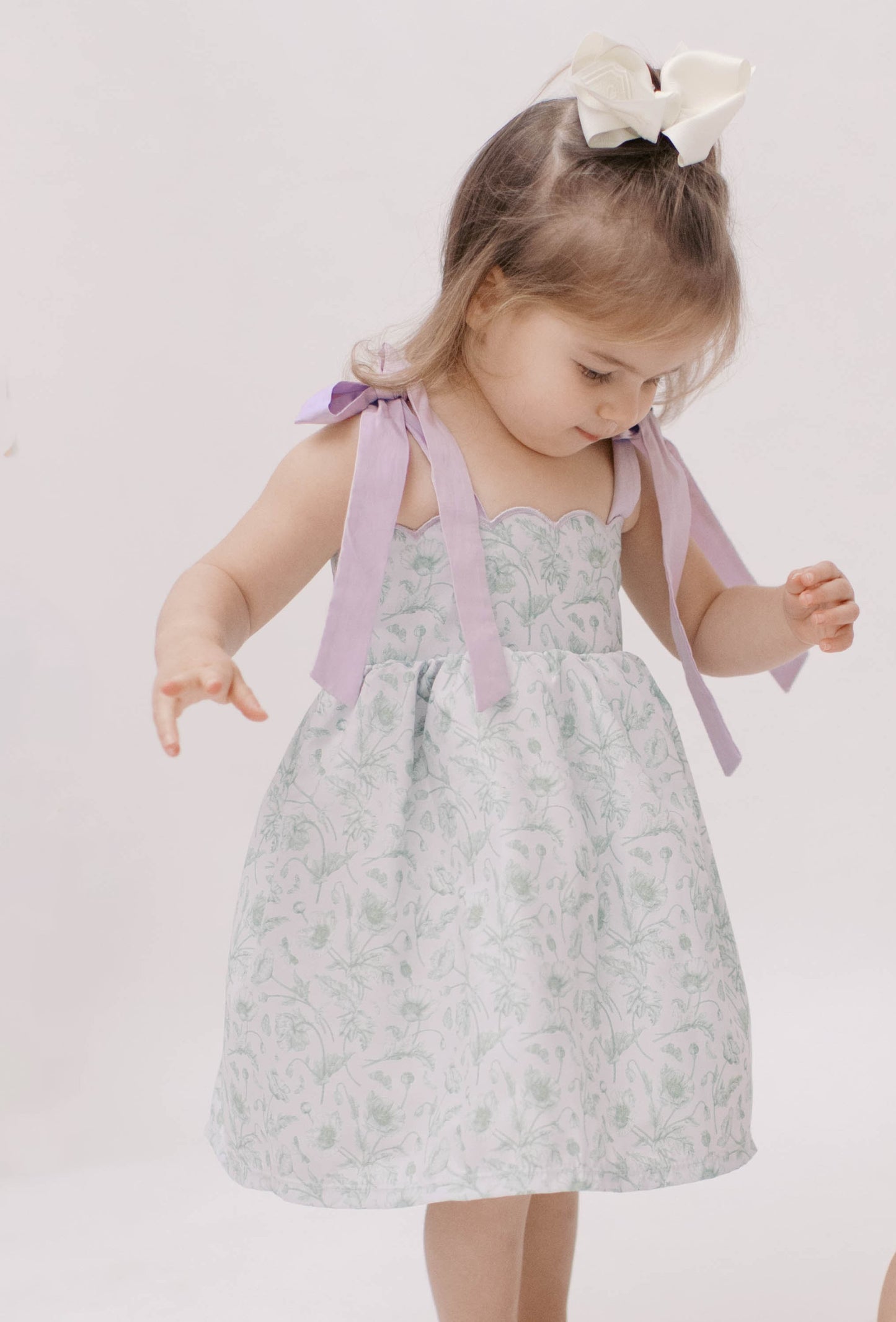 Green floral toile dress with purple shoulder ties and scalloped neckline.