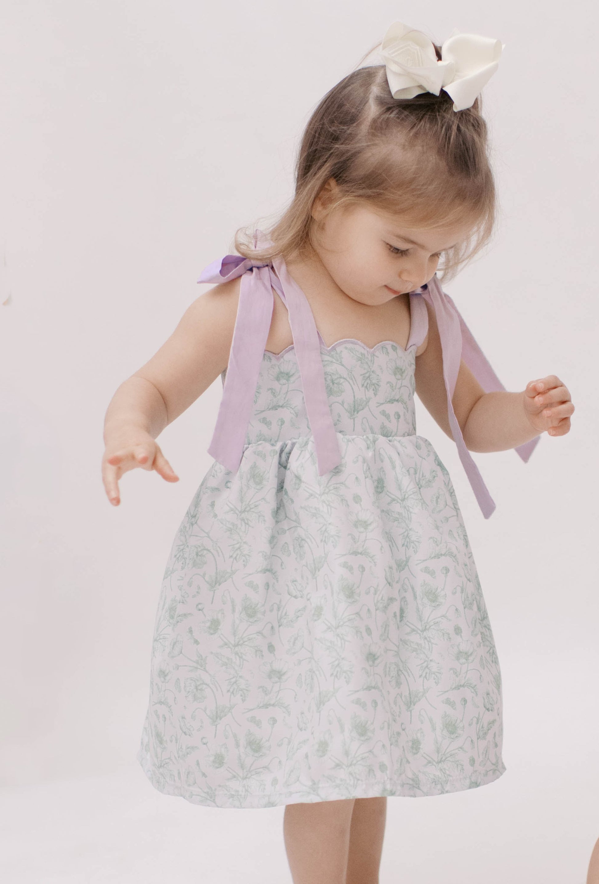 Green floral toile dress with purple shoulder ties and scalloped neckline.
