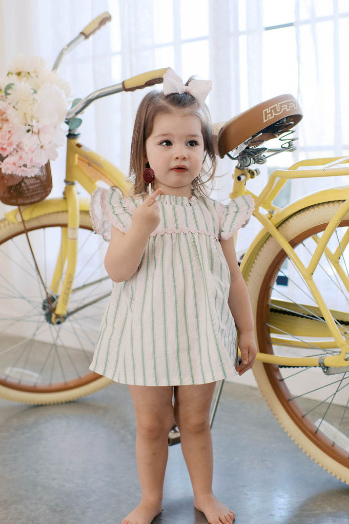 Little baby girl wearing green stripe top with diaper shorts and pink ric rac ruffle top.